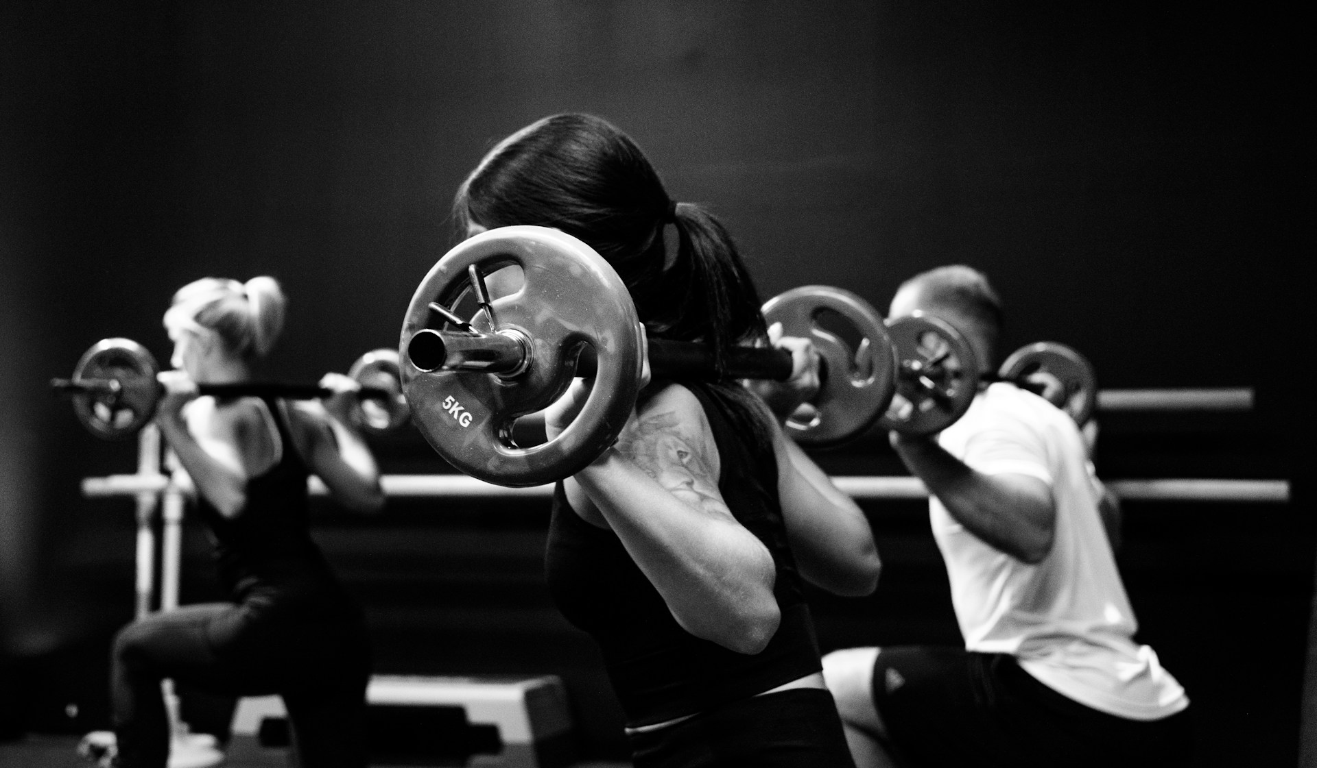 A group of people doing barbell back squats